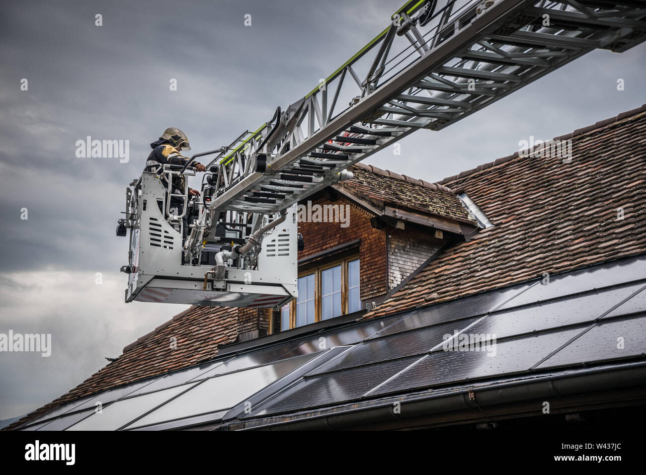 Scala girevole con cestello al di sopra di un tetto con edificio fotovoltaico integrato Foto Stock