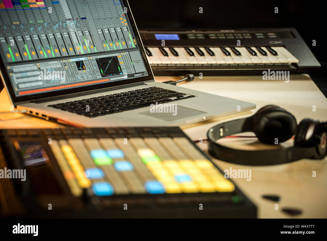 Musica elettronica di produzione. Apple Macbook con Ableton Live music software, spingere midi pad controller, le cuffie Beats e Yamaha Tastiera synth Foto Stock