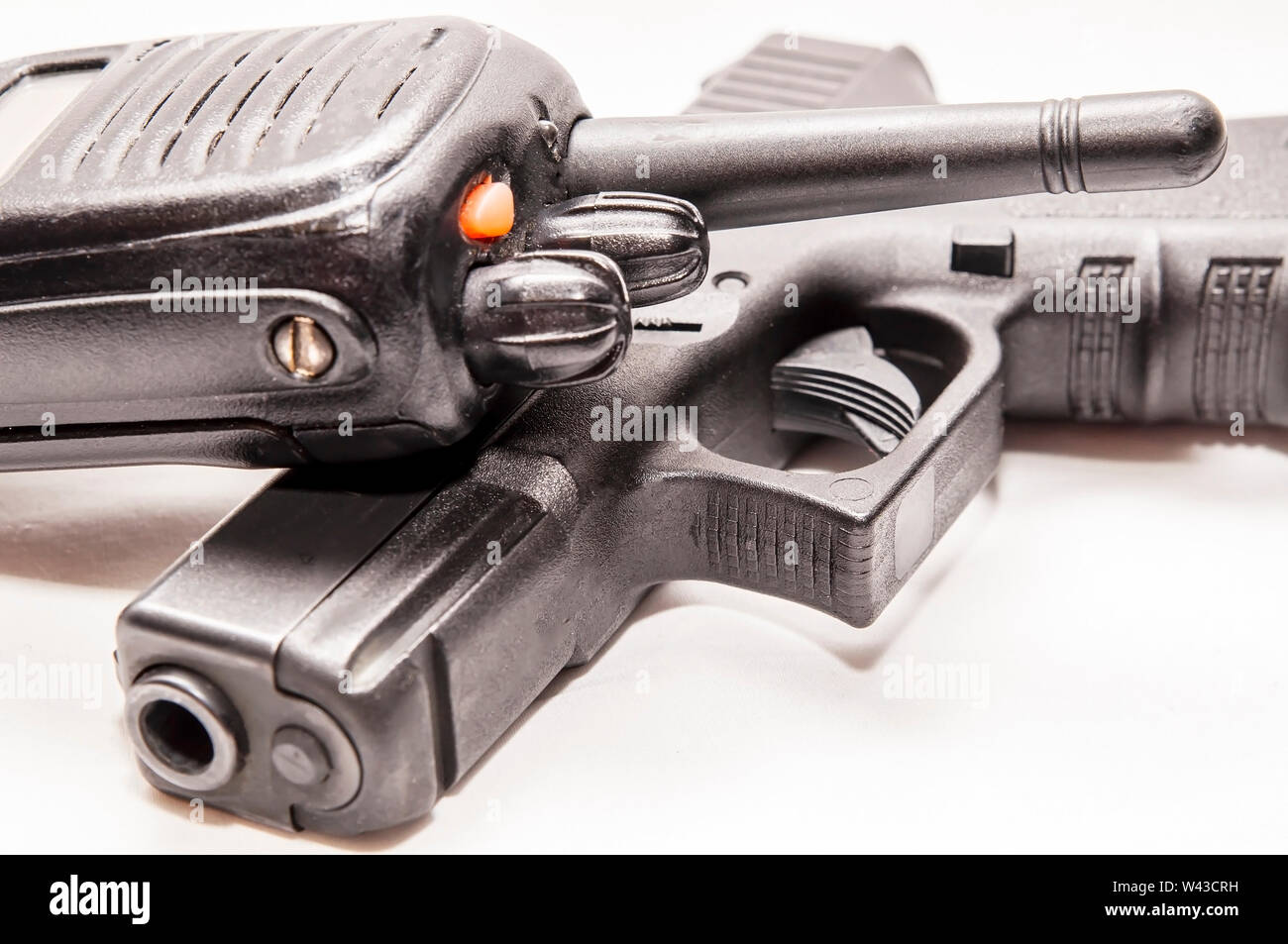 Una radio della polizia recante sulla parte superiore di un nero 9mm pistola con uno sfondo bianco Foto Stock