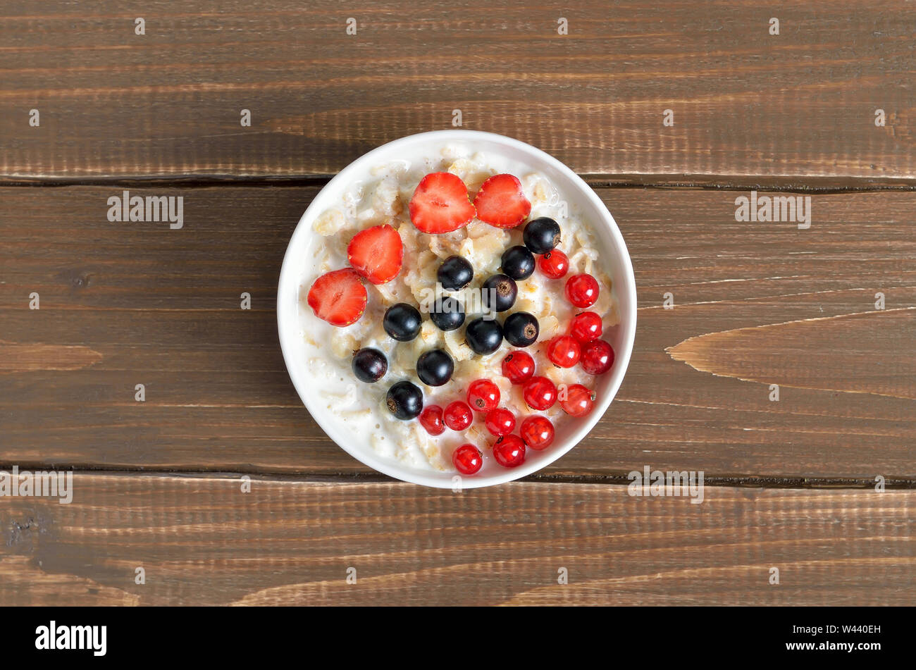 Farina di avena porridge con bacche nella ciotola sul tavolo di legno, vista dall'alto Foto Stock