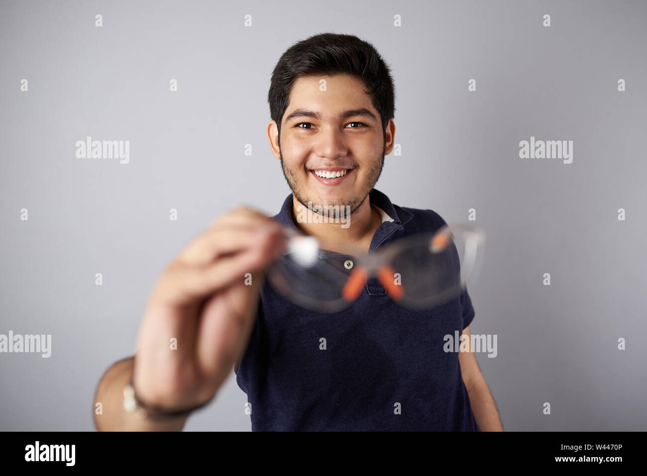 Uomo sorridente con gli occhiali di protezione in grigio studio backgrpound Foto Stock