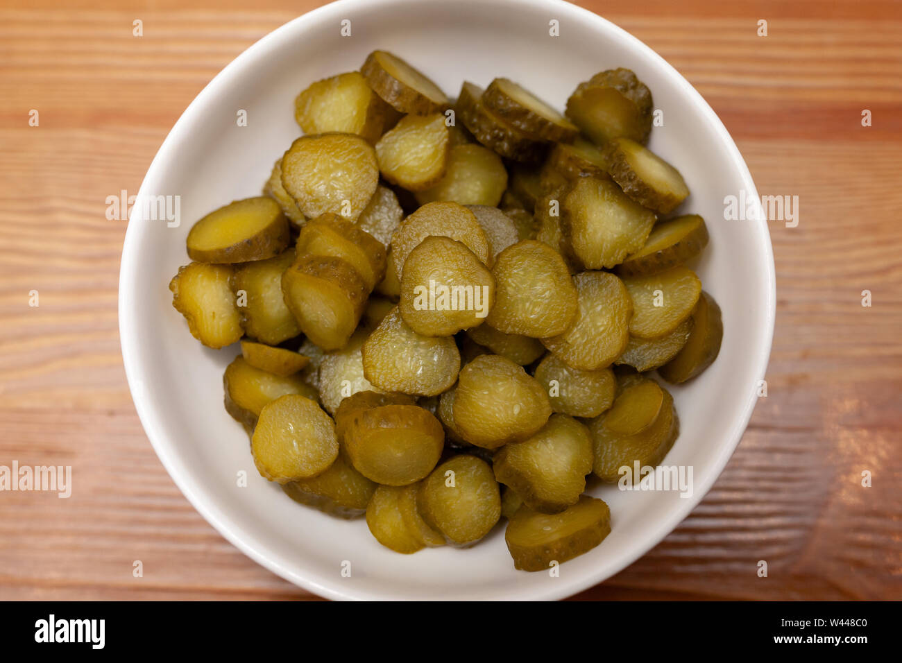Tagliate a fette i cetrioli cetriolini in una ciotola su una tavola di legno Foto Stock