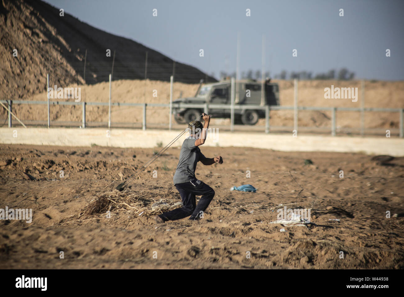 Un dimostrante palestinese utilizza un slingshot per scagliare pietre contro le forze israeliane durante scontri pur dimostrando chiedendo la fine al blocco israeliano della Striscia di Gaza e rivendicano il diritto di tornare alle loro case durante la recinzione di confine tra Israele e la striscia di Gaza nel sud della striscia di Gaza. Foto Stock