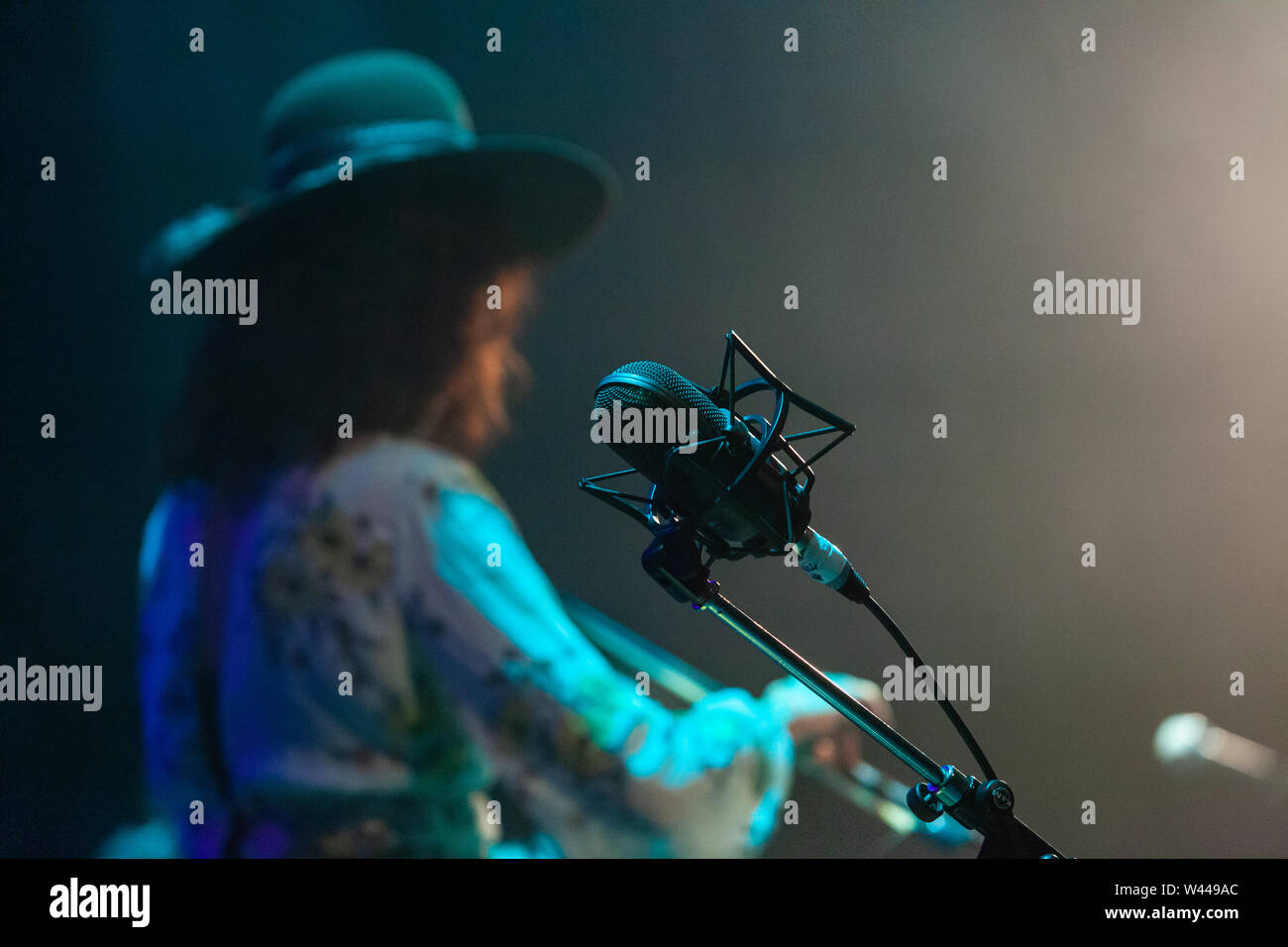 Una vista ravvicinata di un mic stand sul palco durante un concerto di musica. Musicista esegue in background. Membro della band e staging durante il live set. Foto Stock