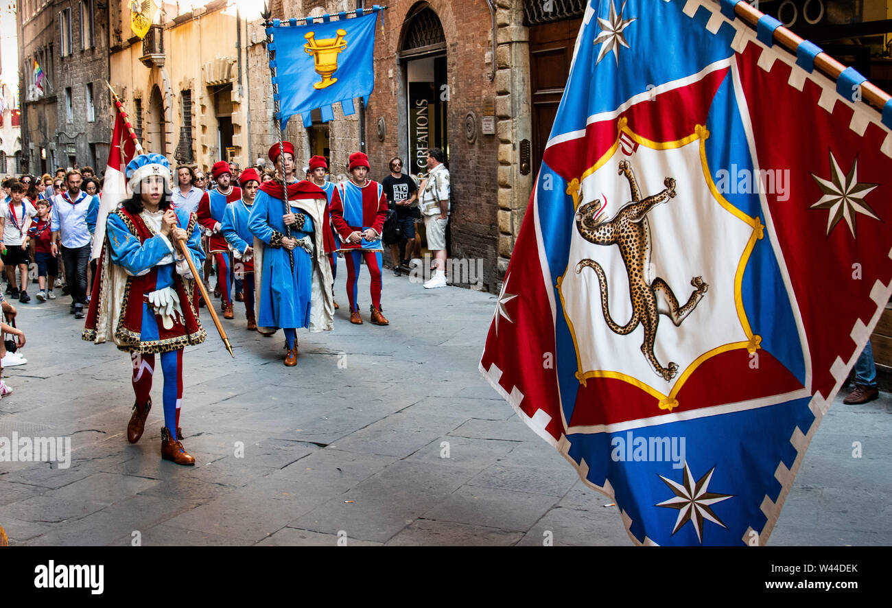 In costume medievale dimostranti con il batterista e bandiere a piedi attraverso le strade di Siena, Italia presso la storica annuale Palio e sfilata Foto Stock