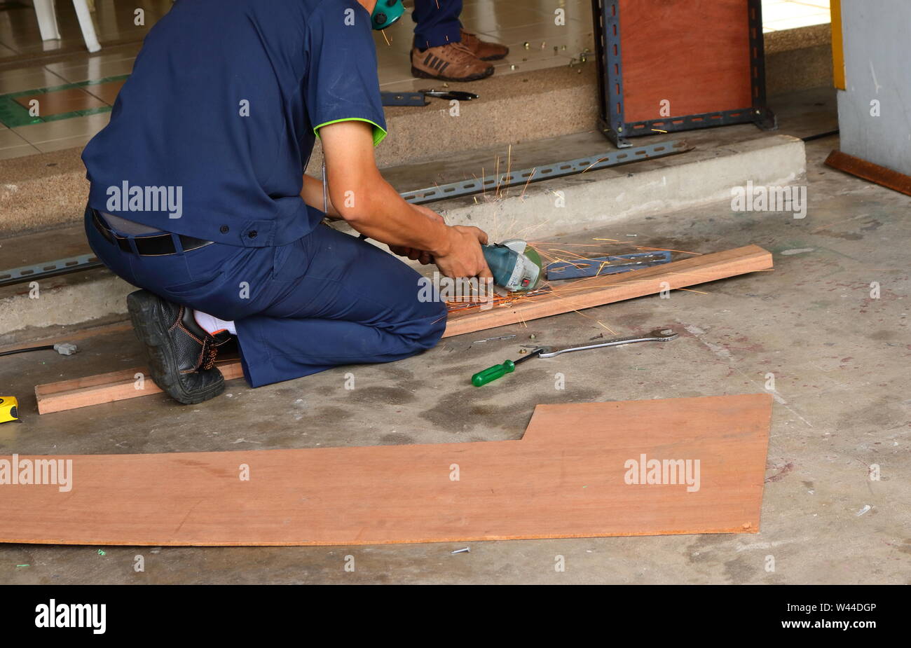 Un lavoratore lavora con un palmare macchina rettificatrice, egli deve concentrarsi sul suo lavoro per la sicurezza Foto Stock