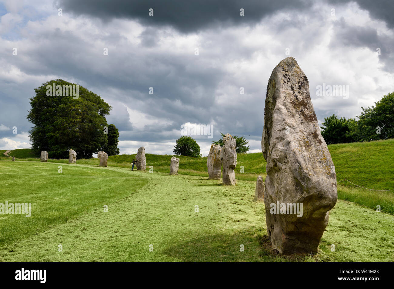 Visitatore toccando un neolitico monolito permanente ad Avebury Henge Inghilterra sud-ovest del bordo del settore della più grande pietra megalitico cerchio nel mondo Foto Stock