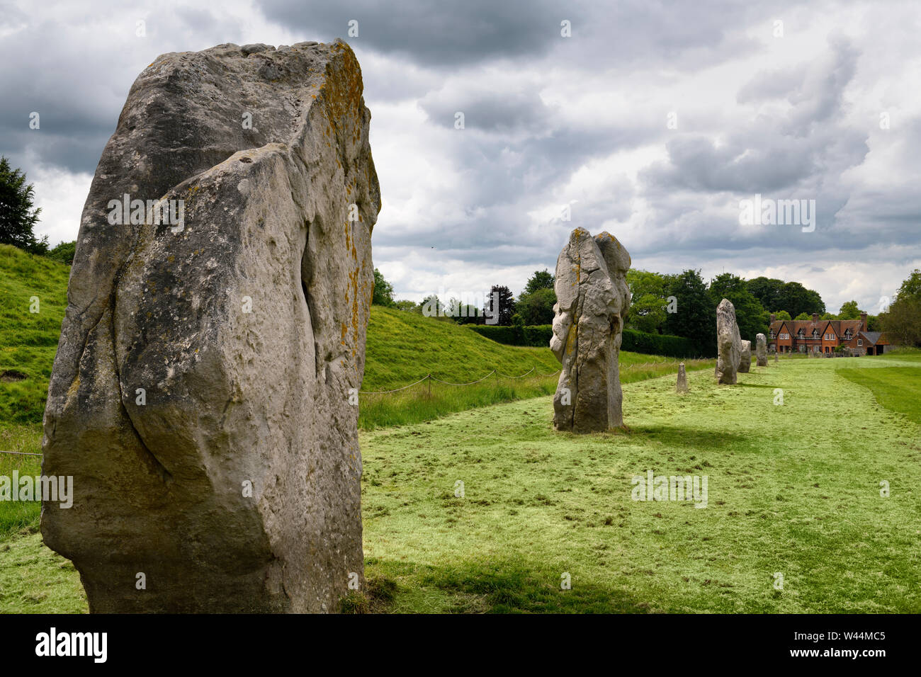 Antiche pietre permanente presso il South West Settore di Avebury Henge con banca e fossato con Fowlers cottage di Avebury Wiltshire, Inghilterra Foto Stock