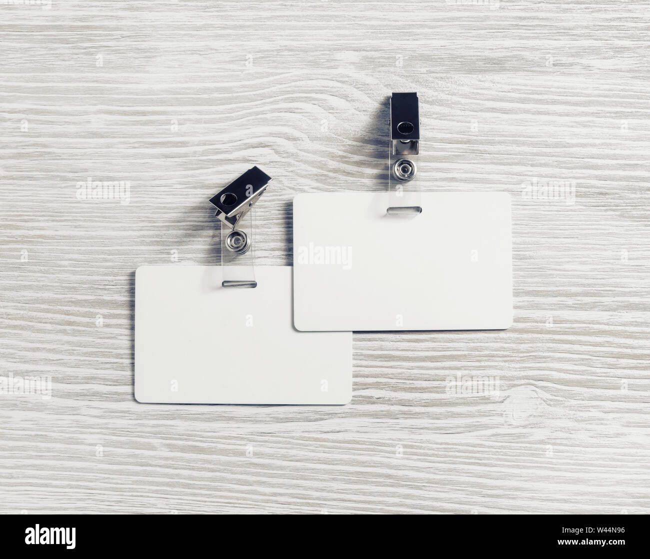 Due blank badge in plastica mockup su legno chiaro sfondo tabella. Empty ID mock up. Copia spazio per il testo. Lay piatto. Foto Stock