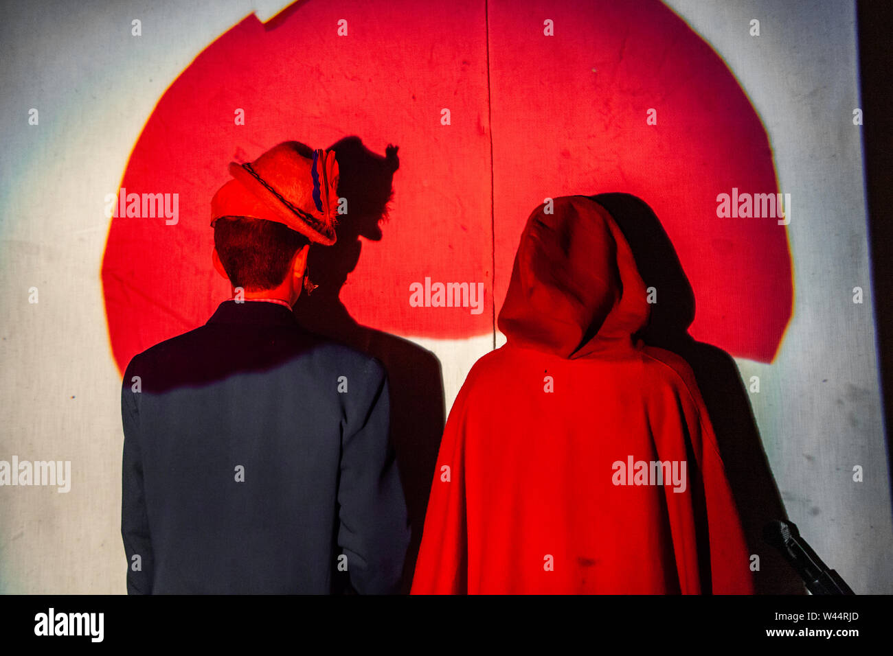 Due giovani sono visto in piedi dietro un sipario sul palco durante una scuola di produzione, vestito in costume di fantasia per reinterpreta la storia. Foto Stock