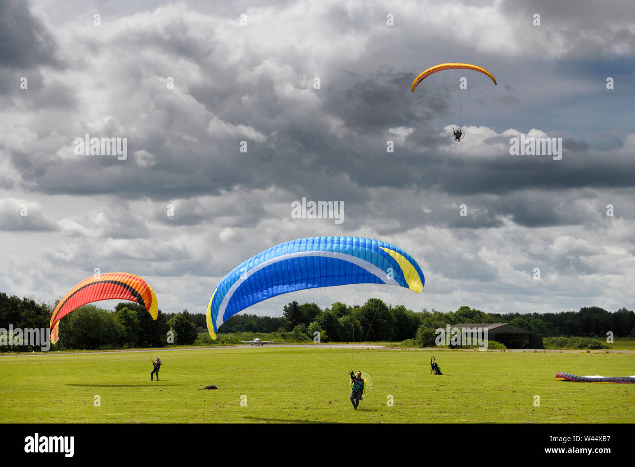 Paramotoring club con il kite pratica sul terreno con e senza motore e un pilota di aerei in arrivo per un atterraggio in Hungerford Inghilterra Foto Stock