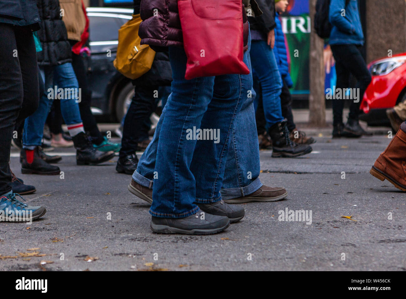 Un basso livello di visualizzare su un ampio gruppo di eco-attivisti a camminare su una strada urbana, gli arti inferiori di persone che indossano jeans e scarpe come si uniscono per il cambiamento. Foto Stock