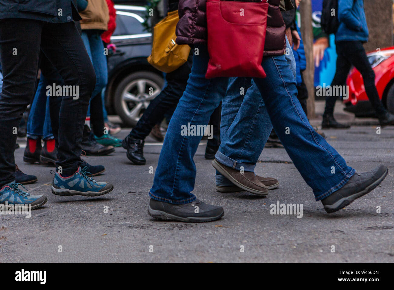 Molte le gambe sono visualizzati in marcia in un centro città come ambientalisti dimostrare insieme, vivace scena di strada nel corso di una protesta della comunità. Foto Stock
