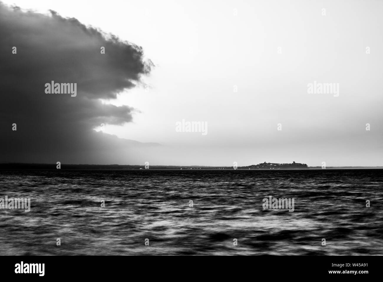 Bellissima vista del lago Trasimeno (Umbria, Italia) al tramonto, con cielo vuoto e una grande nuvola sulla sinistra Foto Stock