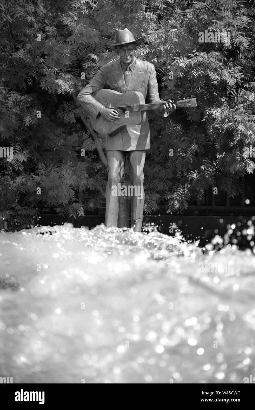 Attiva una fontana di acqua prima che la statua in bronzo di Hank Williams, Sr, strimpellamento la sua chitarra, in RSA complesso torre in Montgomery, AL, Stati Uniti d'America, in bl Foto Stock