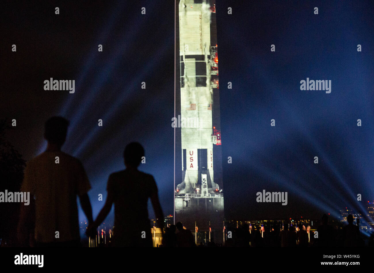 Washington DC, Stati Uniti d'America. Il 19 luglio 2019. Una grande folla di fedeli il Saturn V avviare video proiettato sul lato orientale del Monumento di Washington. La proiezione e spettacolo di luci sono state commissionate dal Museo Nazionale dell'aria e dello spazio in onore del cinquantesimo anniversario di Apollo 11's sbarco sulla luna. Credito: Tim Thulson/Alamy Live News. Foto Stock