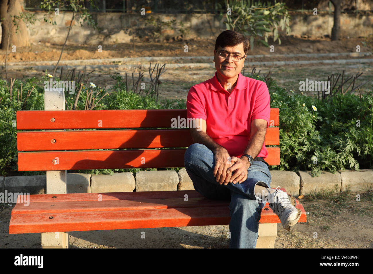 Uomo seduto su una panchina nel parco Foto Stock