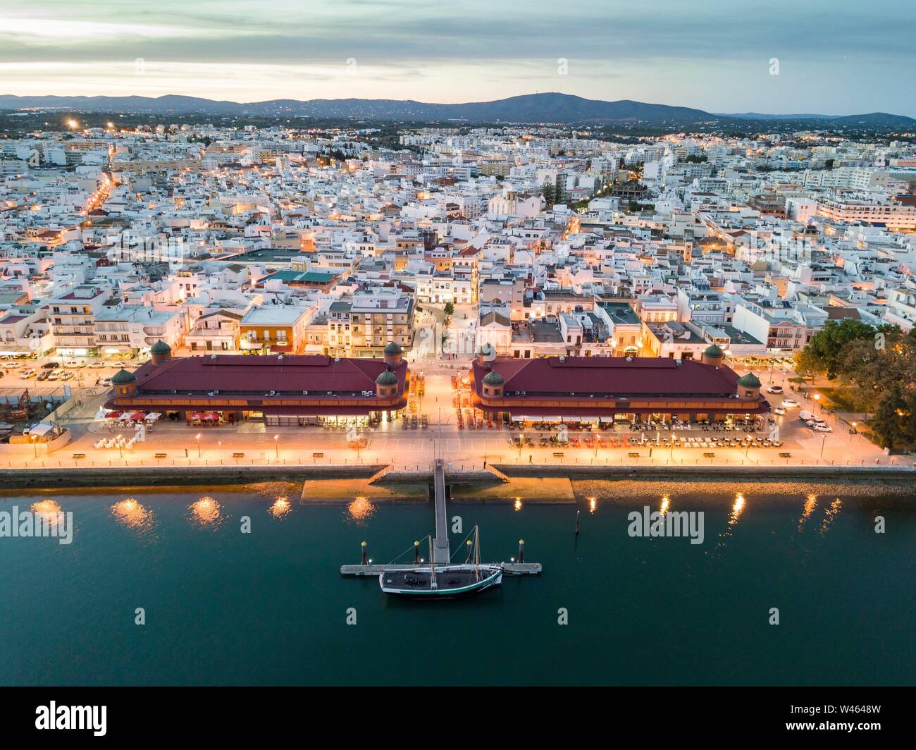 Vista città con due edifici di mercato di sera, fiume Ria Formosa, Olhao, Algarve, PORTOGALLO Foto Stock