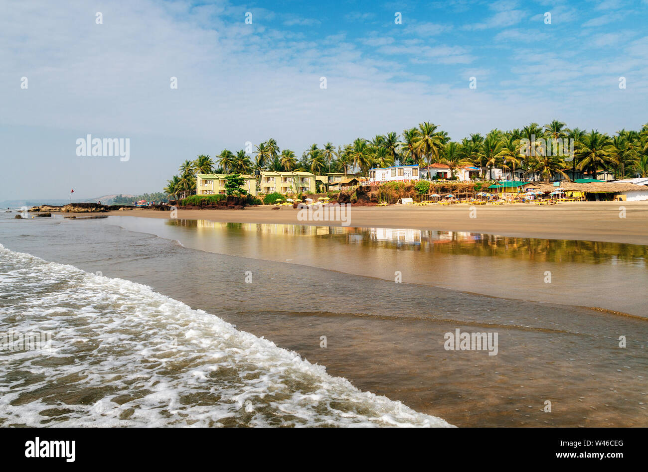 Le pensioni e i lettini sulla spiaggia del Mare Arabico in medio di rocce e di arenaria in Ashvem, Goa, India Foto Stock