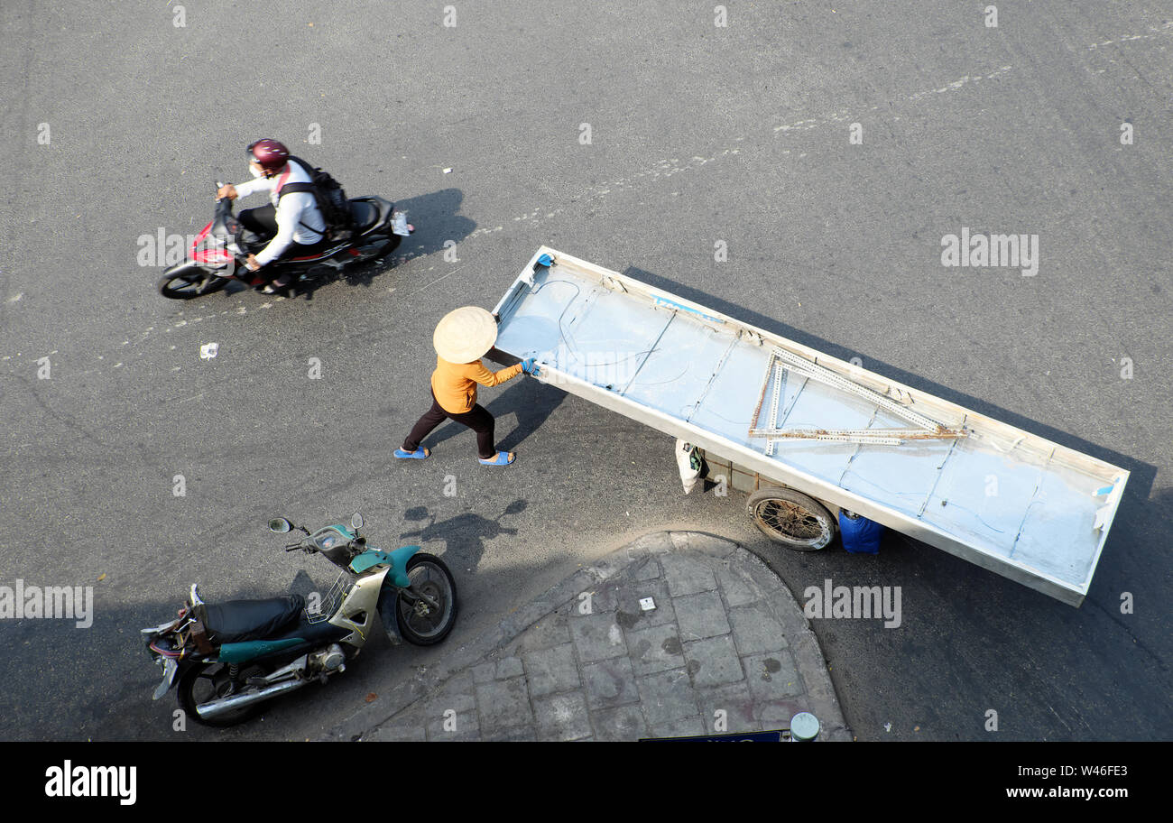 Vista superiore femmina di rottame di ferro il concessionario spingere lungo foglio su carrello a piedi sulla strada a Ho Chi Minh City, Vietnam il giorno Foto Stock