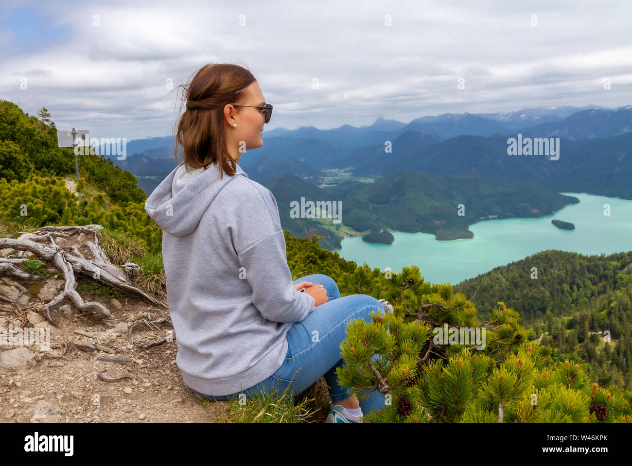 Giovane donna seduta sulla montagna e godere la vista, Hergostand, Baviera, Germania Foto Stock