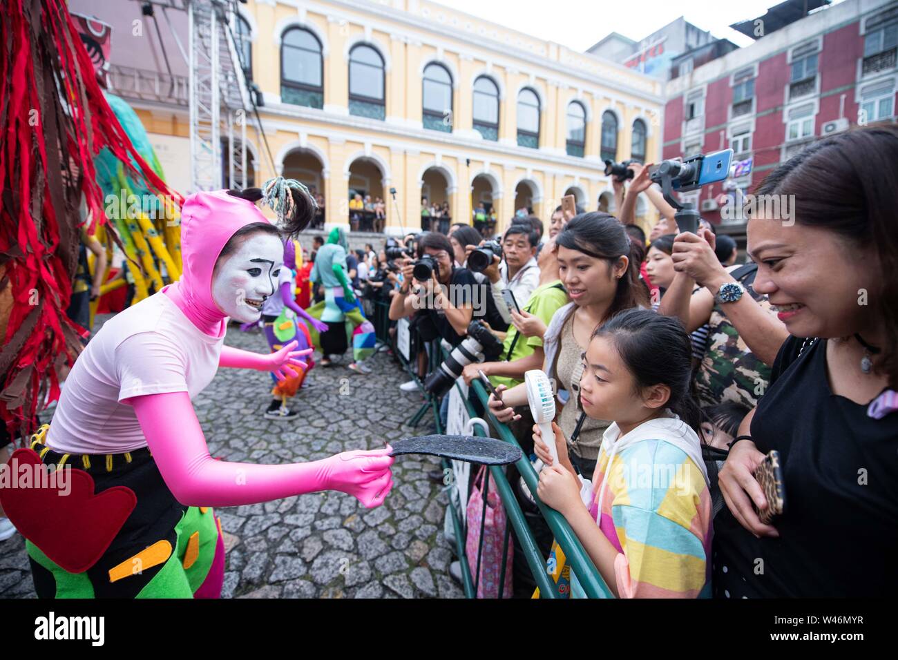 (190720) -- MACAO, luglio 20, 2019 (Xinhua) -- esecutori interagiscono con i turisti durante una parata della International Youth Festival di danza nel sud della Cina di Macao, luglio 20, 2019. La parata iniziato dalle Rovine di San Paolo e hanno marciato attraverso il centro storico di Macao. (Xinhua/Cheong Kam Ka) Foto Stock
