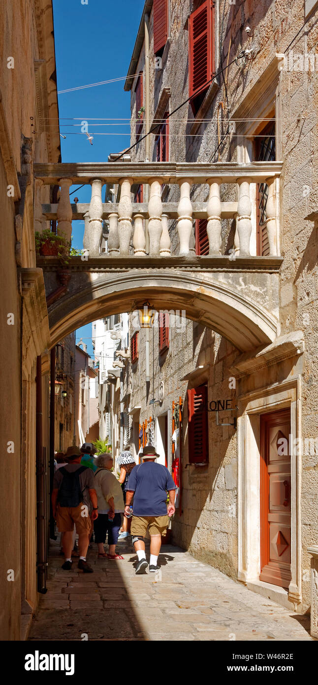 Vecchia stretta strada pedonale; xv secolo; affollato, persone, piccolo ponte in pietra attraverso molti fili di overhead, scena cittadina, Dalmazia; la città di Korcula; Croato Foto Stock