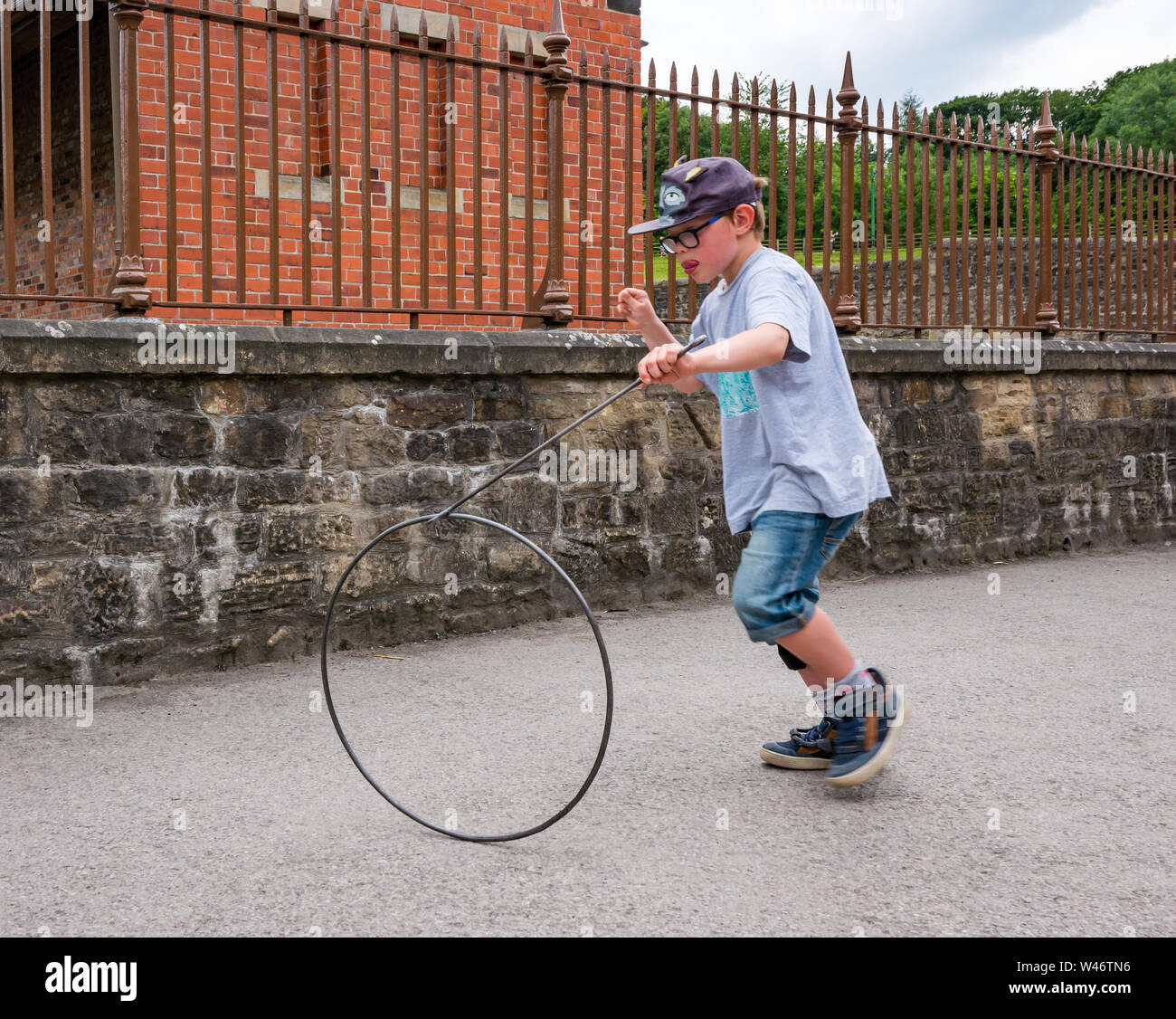 8 anno vecchio ragazzo giocando in vecchio stile hoop gioco di rotolamento, Beamish museo vivente, County Durham, England, Regno Unito Foto Stock