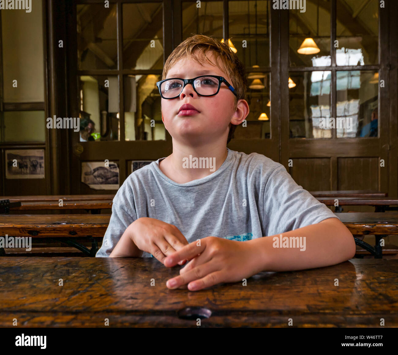 8 anno vecchio ragazzo attento, seduti al vecchio banco di scuola, Beamish museo vivente, County Durham, England, Regno Unito Foto Stock