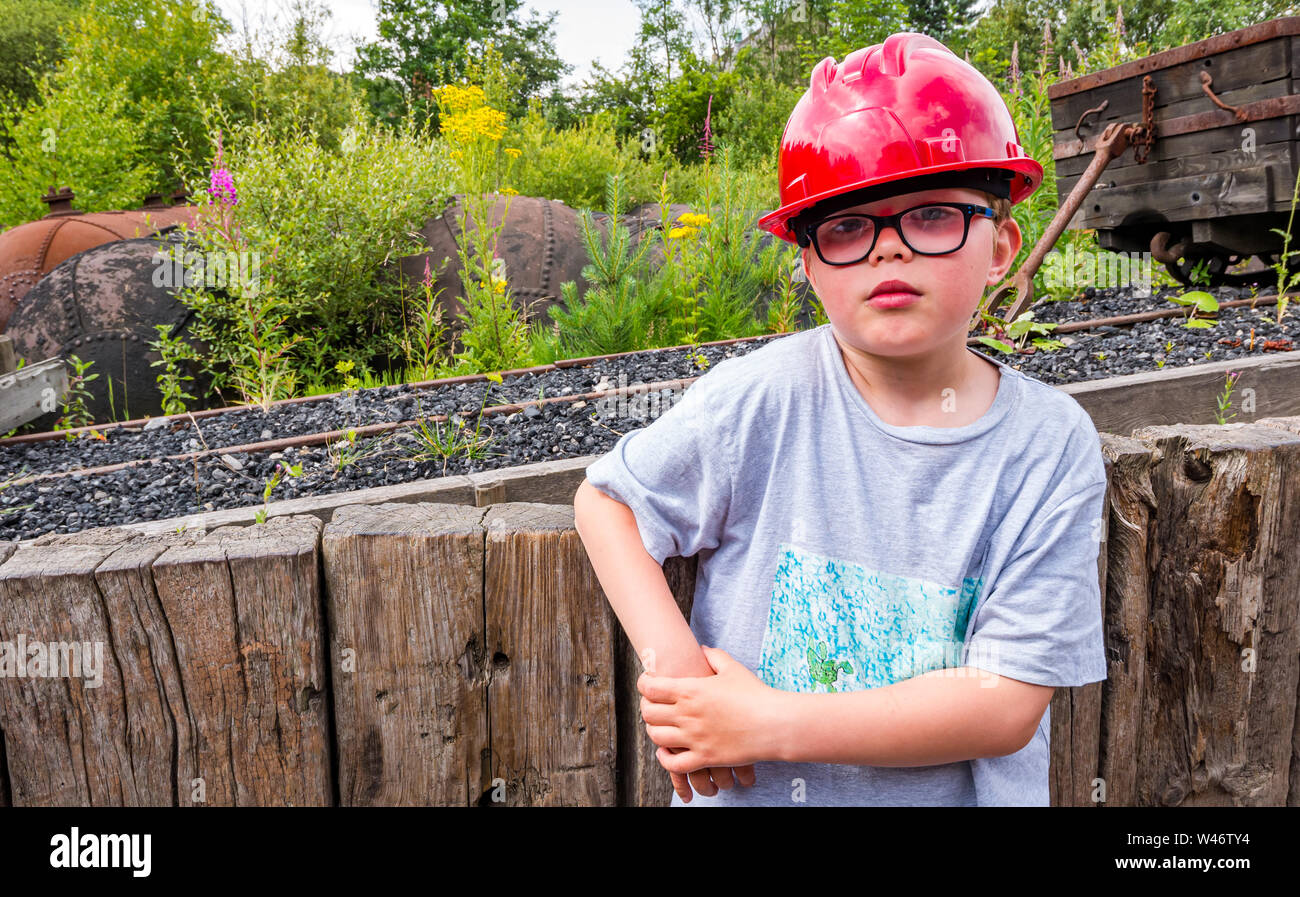 8 anno vecchio ragazzo indossa elmetto in pit-villaggio della miniera di carbone, Beamish museo vivente, County Durham, England, Regno Unito Foto Stock