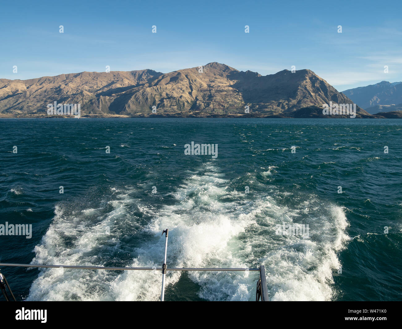 Spumosa scia di una barca sul Lago Wanaka, con cielo blu e vista sulle montagne in distanza Foto Stock