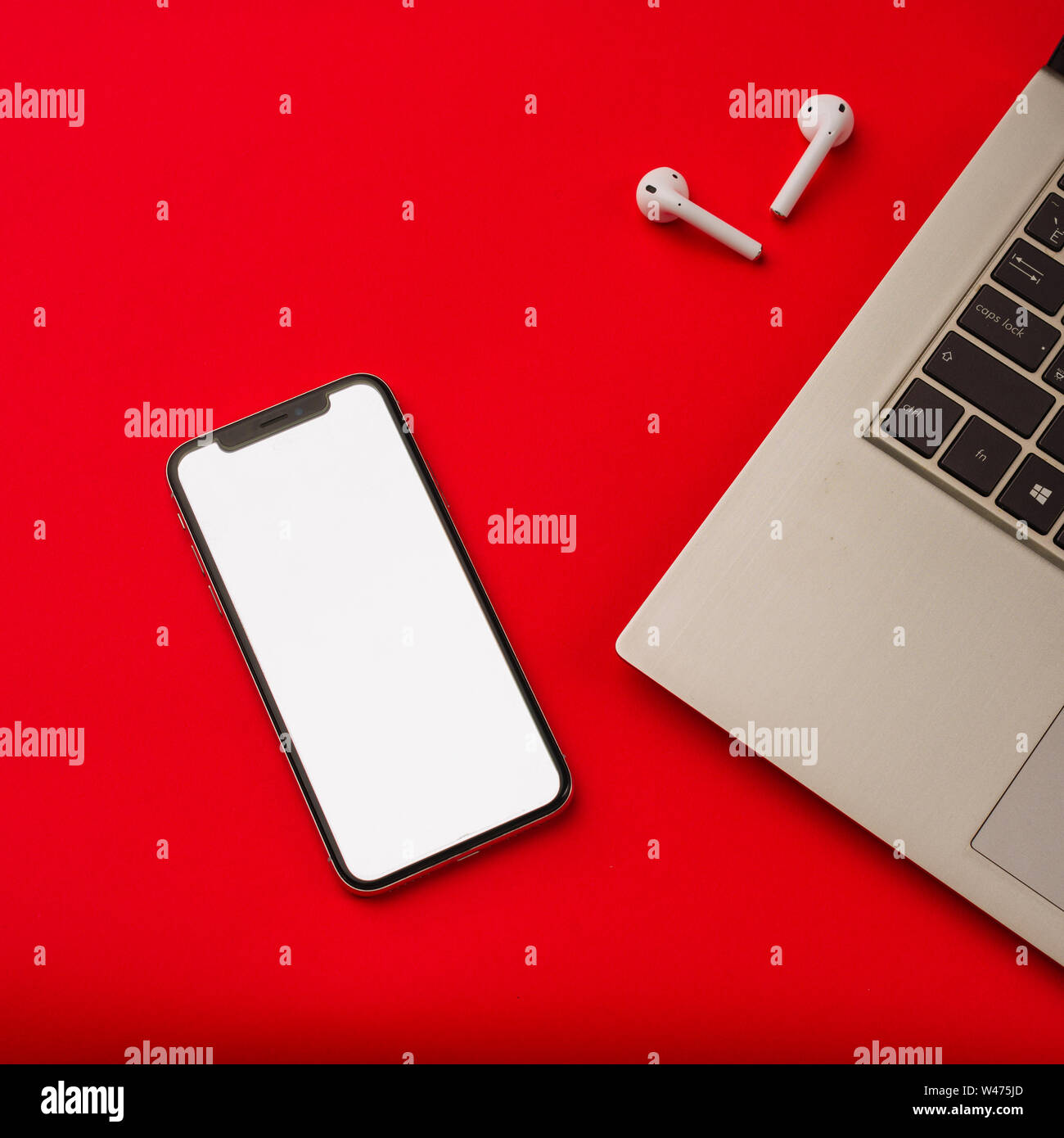 Tula, Russia - maggio 24,2019: Apple iPhone X e Airpods su sfondo rosso con notebook. Lo schermo dello smartphone è bianco. Mockup. Foto Stock