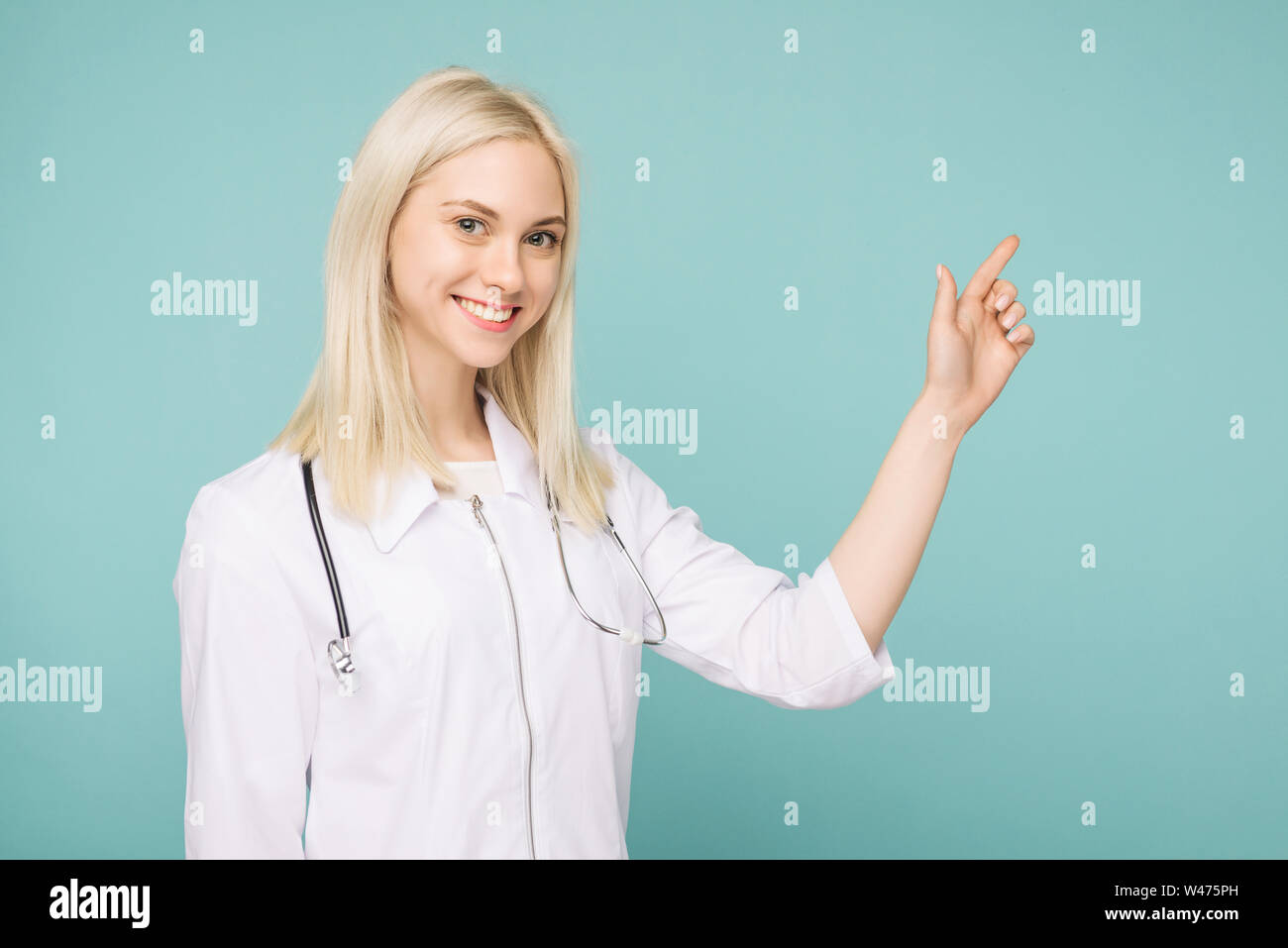 Ritratto di un giovane attraente medico donna in camice bianco su sfondo blu Foto Stock