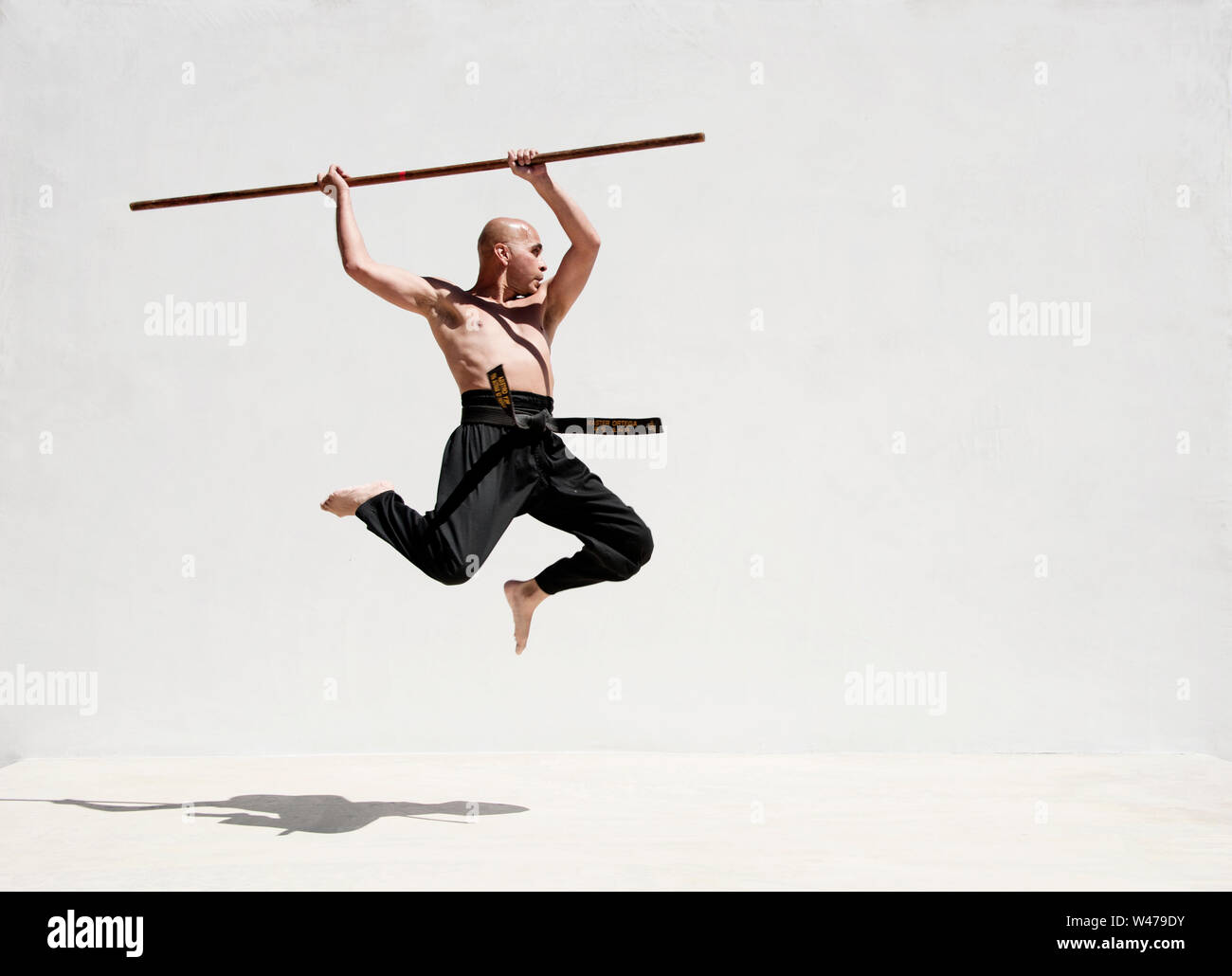 La cintura nera uomo praticanti di arti marziali con un lungo bastone. Foto Stock