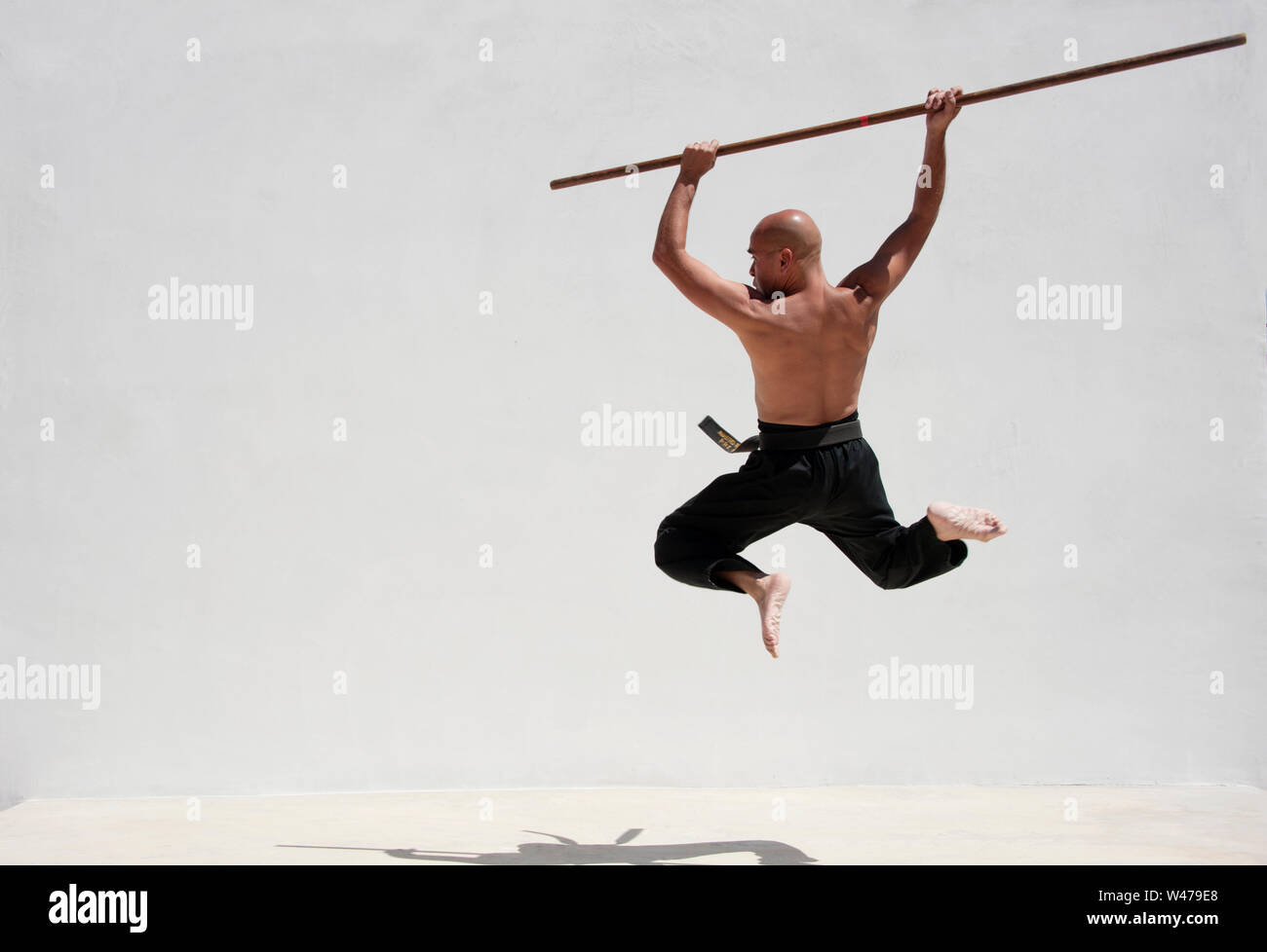 La cintura nera uomo praticanti di arti marziali con un lungo bastone. Foto Stock