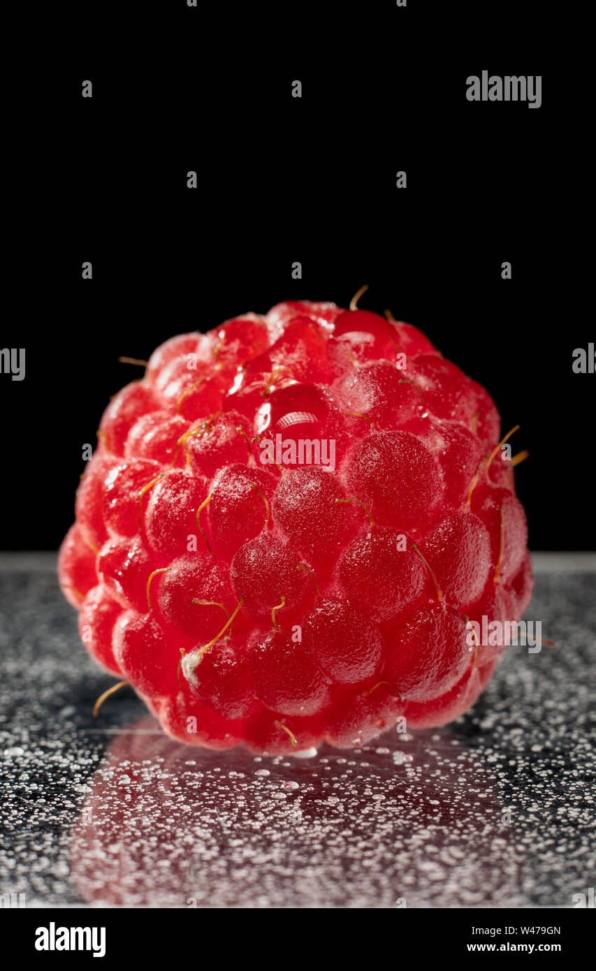 Fresco e naturale lampone berry macro vitamine per gli esseri umani su uno sfondo scuro. Isolare. Foto Stock