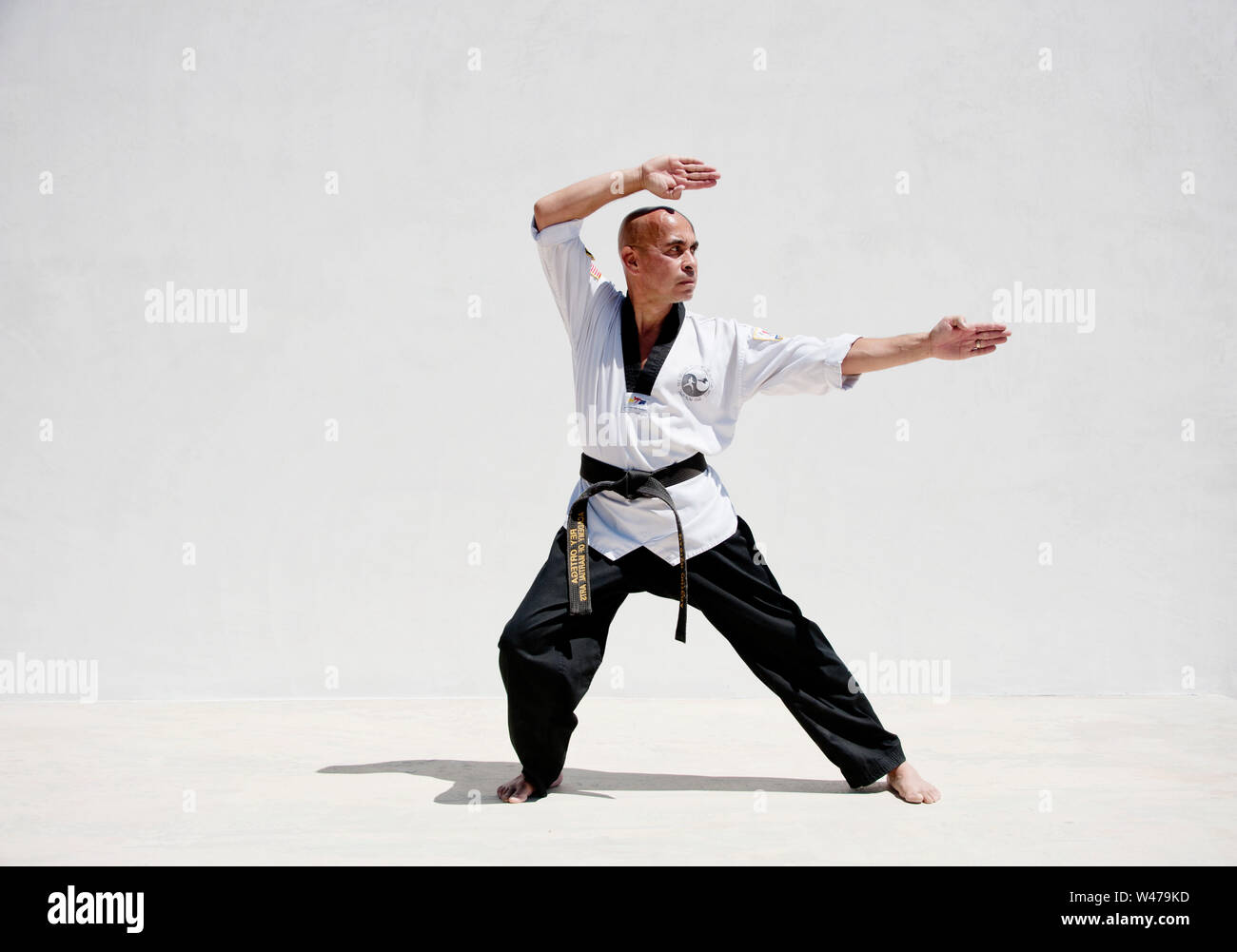 La cintura nera Sensei istruttore di arti marziali dimostrando Taekwondo modulo. Egli è un maestro e istruttore come indicato dalla sua uniforme e forma. Foto Stock