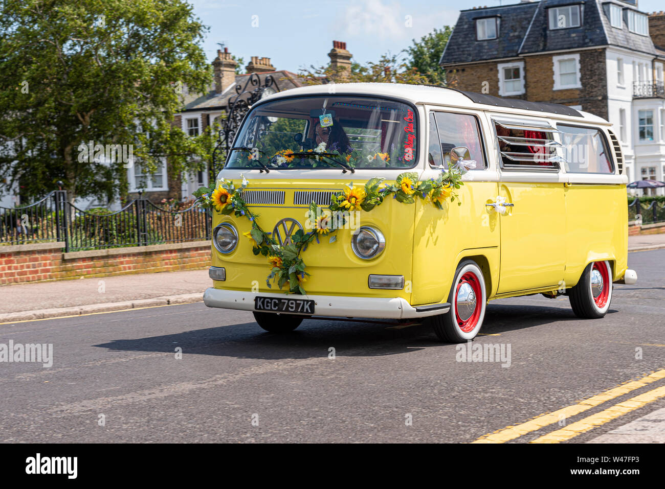 Giallo VW camper van Volkswagen bus del bus di Wolfsburg equipaggio piccolo autobus gialli con stile hippy fiori poggiata sulla parte anteriore. Noleggio veicolo business Foto Stock