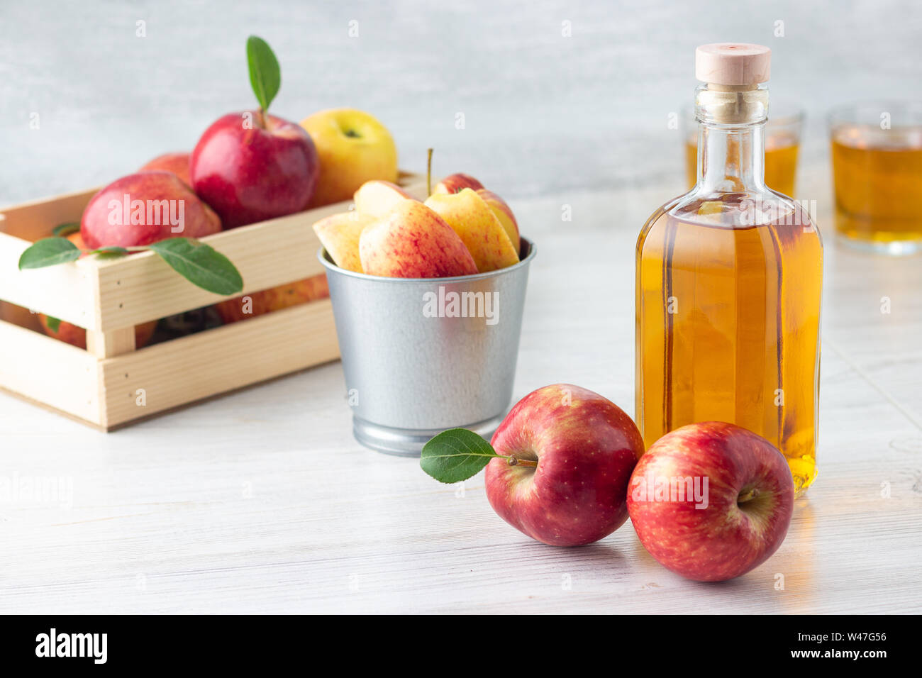 Un sano cibo biologico. Sidro di mela aceto o succo di frutta in una bottiglia di vetro e fresche Mele rosse su uno sfondo luminoso. Foto Stock