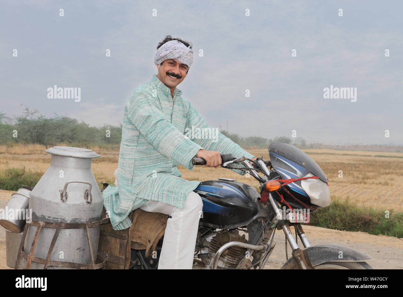 Lattaio indiano consegnare latte su una motocicletta Foto Stock