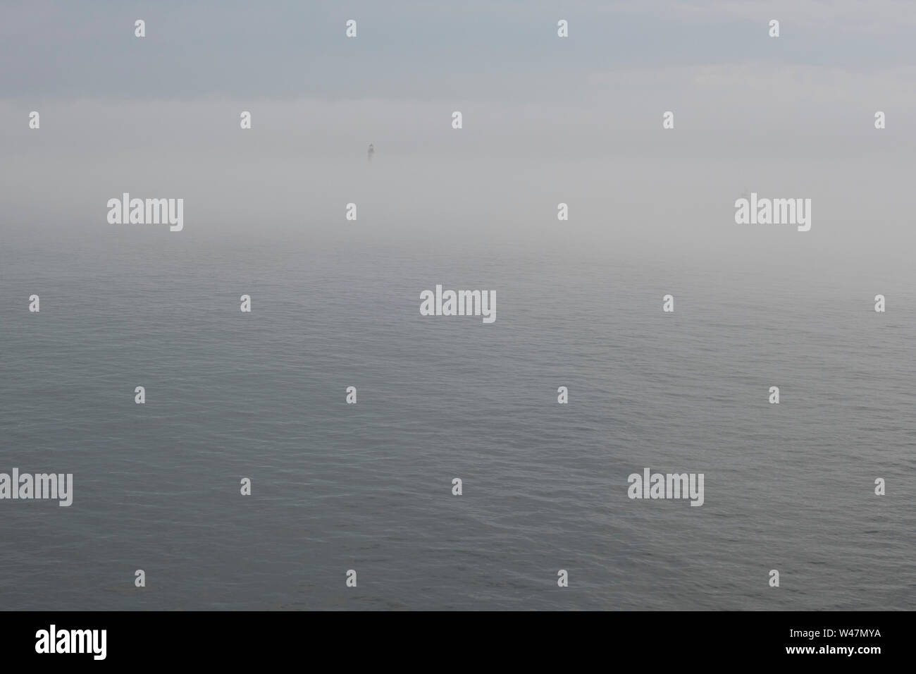 Il faro in distanza su un oceano di nebbia Foto Stock