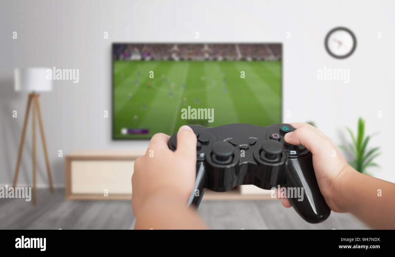 Ragazzo giocare a calcio gioco su console di gioco su grandi TV in soggiorno. Foto Stock