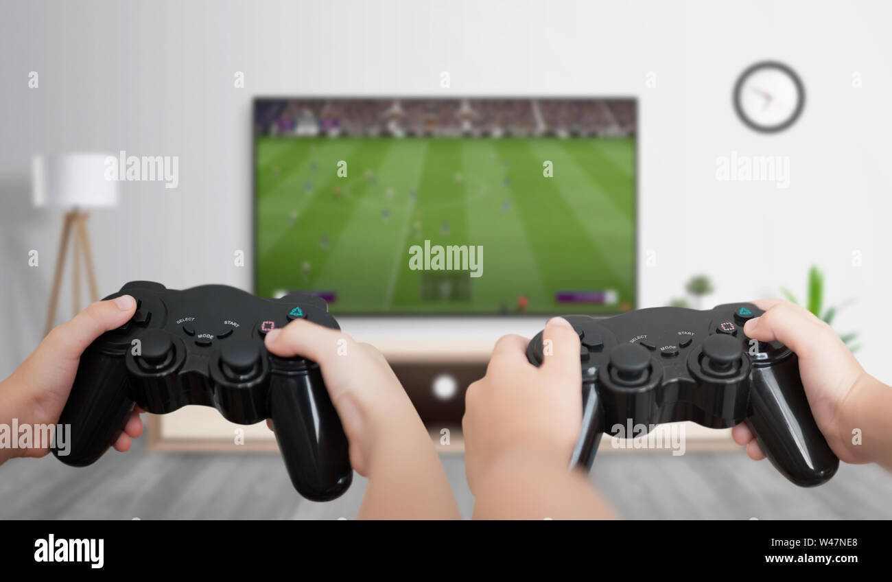 Ragazzi giocare a calcio sulla console di gioco su un grande televisore in camera. Il concetto di divertimento e giochi per gli amici. Foto Stock