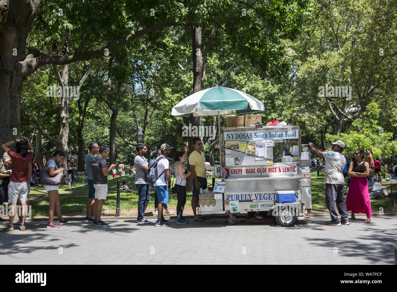 Molti Indiani e altri la linea fino a un popolare a sud il cibo indiano venditore in Washington Square Park a pranzo nel Greenwich Village di New York City. Foto Stock