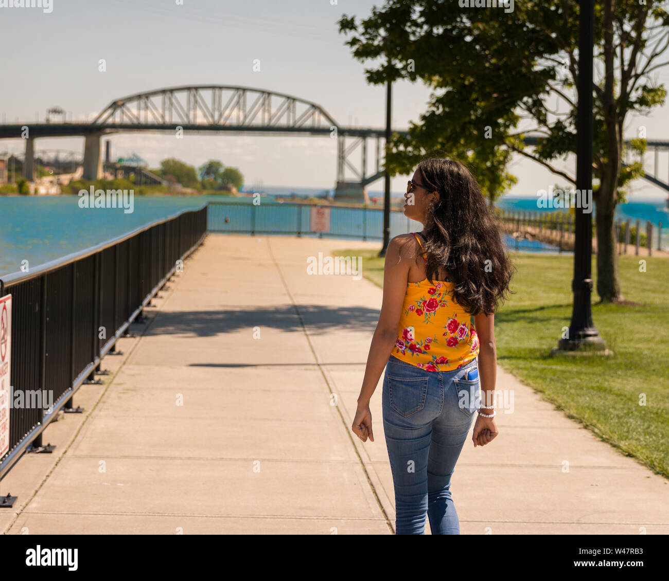 Ragazza adolescente camminando sul marciapiede lungo l'acqua. Foto Stock