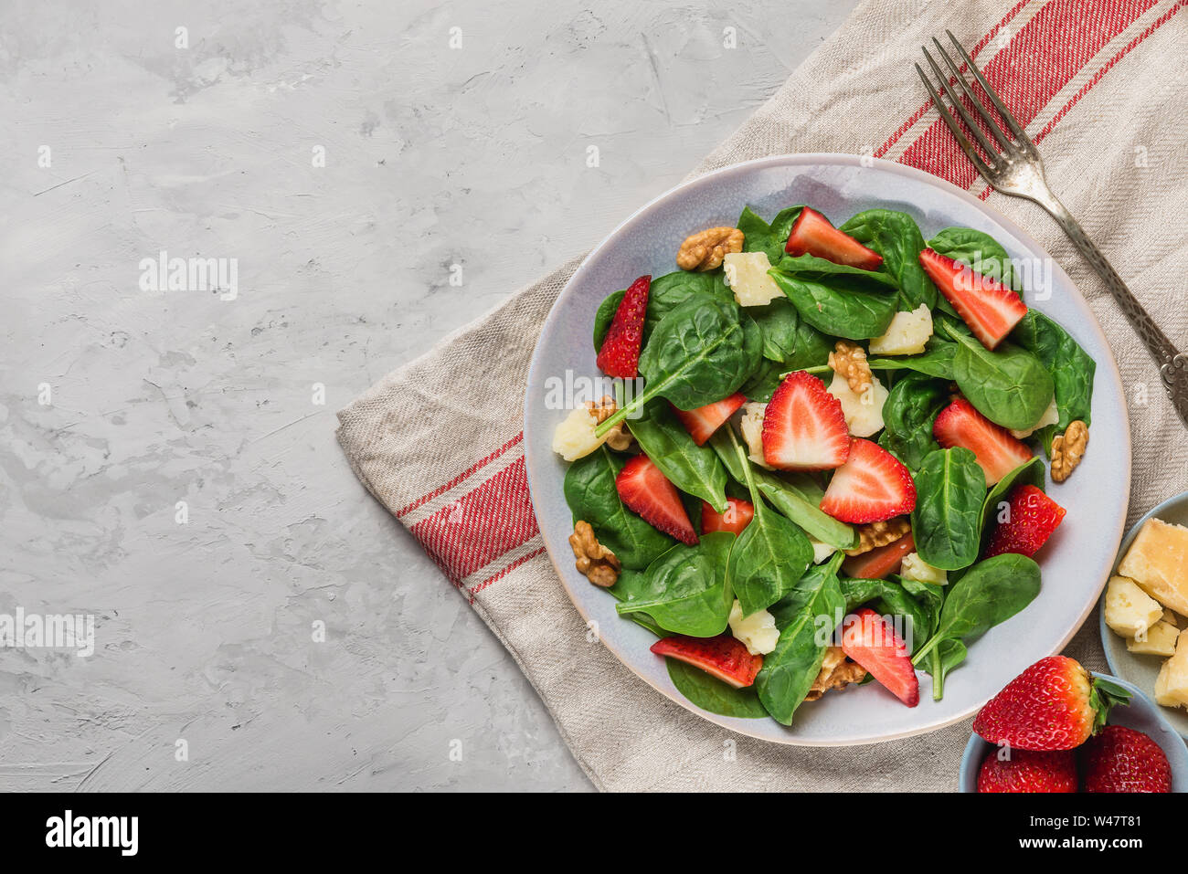 Insalata estiva con foglie di spinaci, fragola, parmigiano, olio di oliva e noci. sana dieta cheto cibo. vista superiore Foto Stock