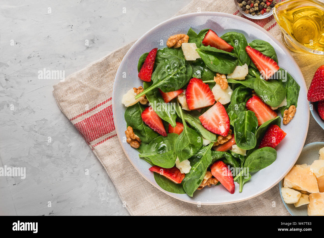 Estate insalata di fragole con foglie di spinaci, formaggio parmigiano, olio di oliva e noci. sana dieta cheto cibo. vista superiore Foto Stock