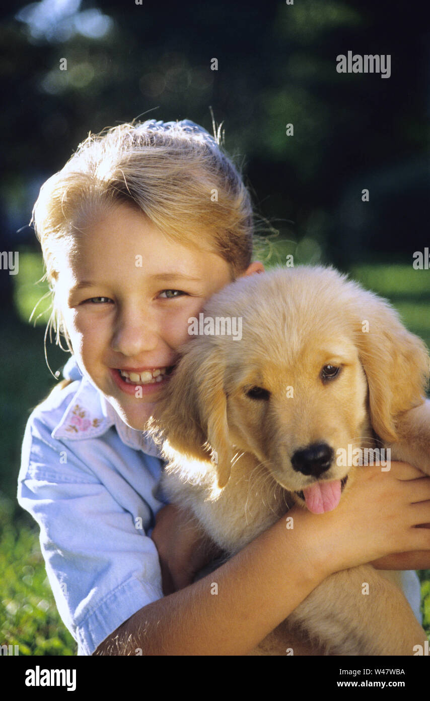 Giovane ragazza tenendo un golden retriever cucciolo Foto Stock