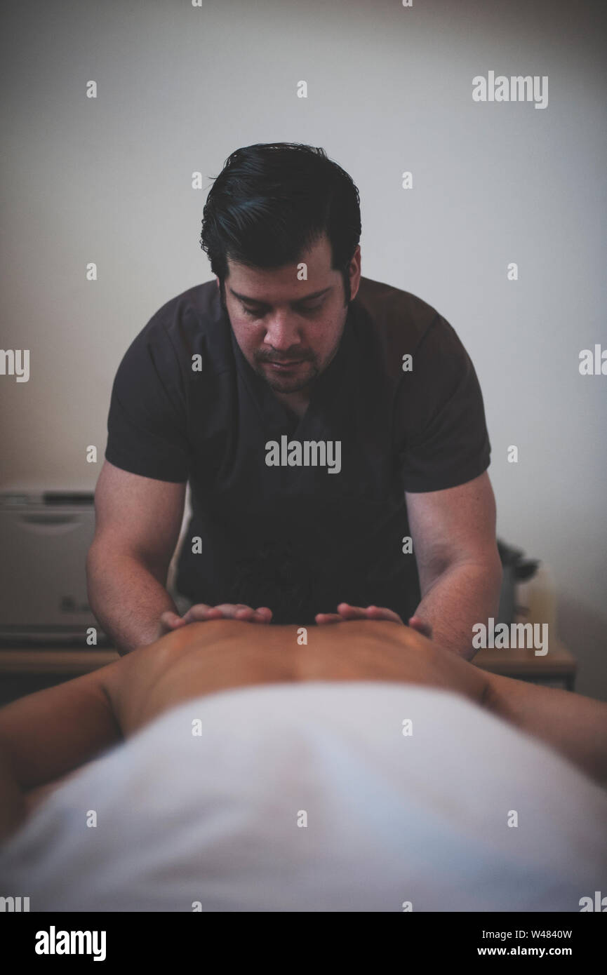 Terapista del sesso maschile dando donna client di terapia di massaggio la carrozzeria. L'uomo terapeuta è ispanico e il suo cliente è caucasiche. Foto Stock