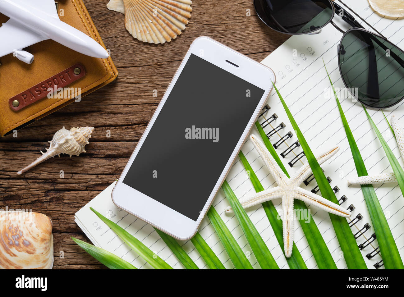 Estate vacanze piano di viaggio smartphone mockup concetto di sfondo. Lay piatto mobile phone mock up modello con passaporto, di foglie di palma, il Seashell, starfi Foto Stock